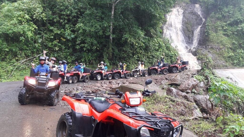 Guests riding red ATV quad bikes on a jungle trail
